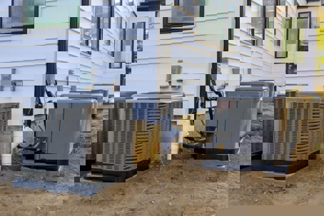 Several HVAC units are installed outside a white house.