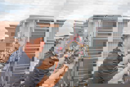 A technician repairing an AC's outdoor unit