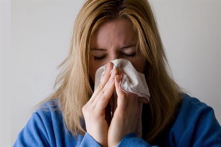A woman sneezing due to allergies