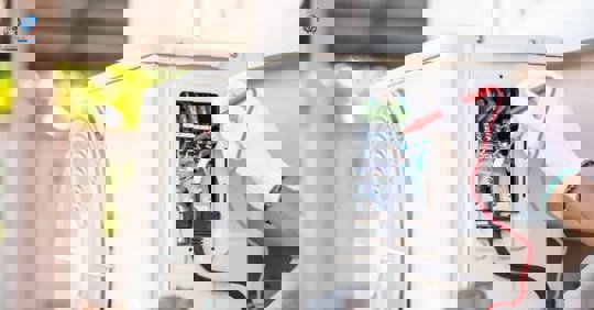 An AC technician is diagnosing an air conditioning unit with a multimeter.