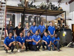 A group of HVAC technicians are standing together, posing for a photo in a work environment.